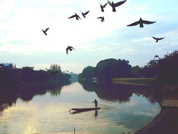 Silhouette man flying over lake against sky