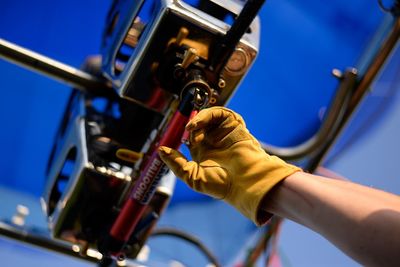 Cropped hand wearing glove by hot air balloon engine