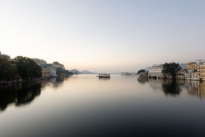 Reflection of buildings in river against clear sky