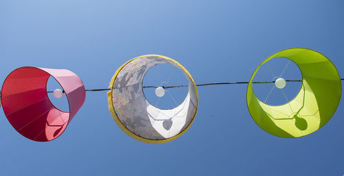 Low angle view hanging lamps against clear blue sky