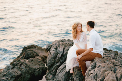 Young couple on rock at sea shore