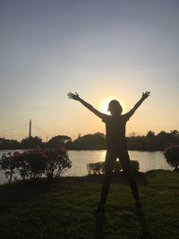 Silhouette person standing on shore against sky during sunset