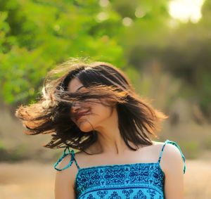 Young woman tossing hair while standing outdoors