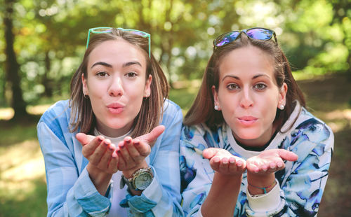 Portrait of friends blowing kiss at park