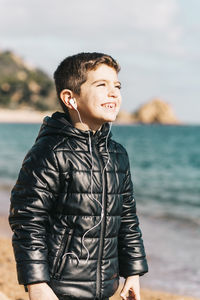 Full length of smiling man standing against sea