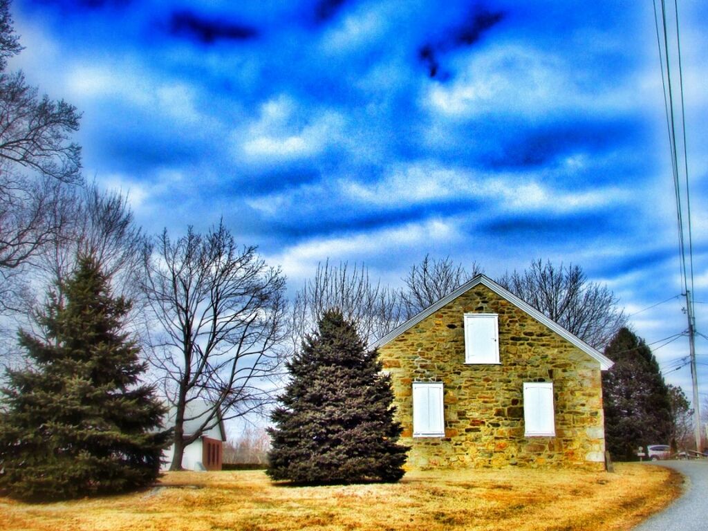 sky, architecture, built structure, building exterior, cloud - sky, tree, house, bare tree, cloud, blue, cloudy, field, nature, tranquility, outdoors, no people, grass, day, residential structure, landscape