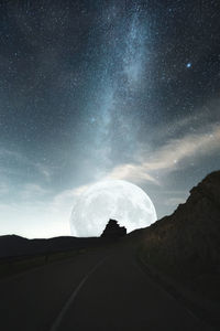 Road leading towards moon at night