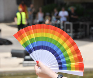 Cropped hand of woman holding colorful folding fan
