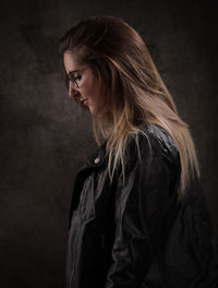 Young woman standing against black background