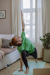 Woman with hand raised practicing yoga at home