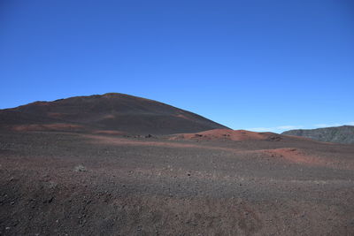 Scenic view of arid landscape against clear blue sky