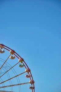 Low angle view of rollercoaster against clear blue sky