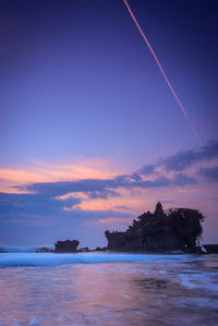 Scenic view of tanah lot temple by the sea against sky at sunset