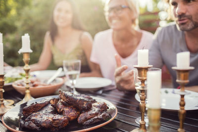 Couple and female friend sitting at dining table during garden party in back yard