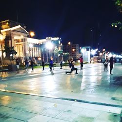 People on illuminated street at night