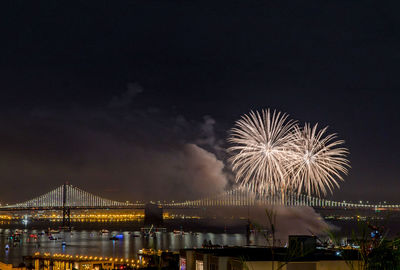 Low angle view of firework display over river at night