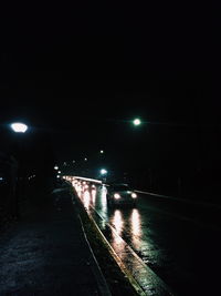 Illuminated road in city during rainy season at night