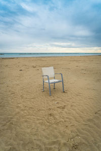 Deck chairs on beach against sky