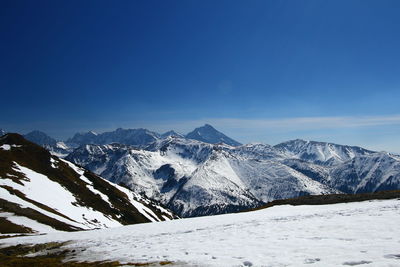 Scenic view of snowcapped mountains against blue sky