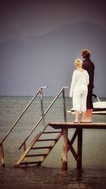 Man standing on railing against sea