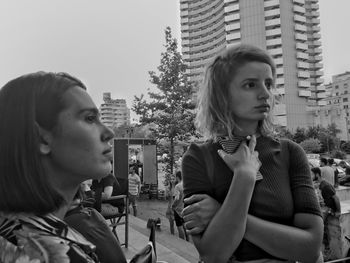 Women looking away against buildings in city