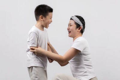 Side view of friends standing against white background