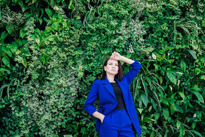 Beautiful woman standing against ivy covered wall