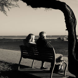 Rear view of woman sitting on beach