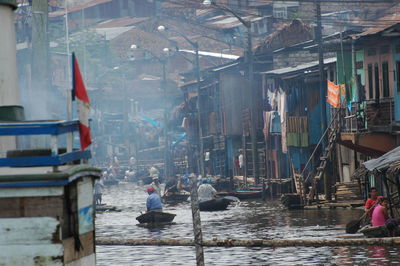 People in canal amidst buildings in city