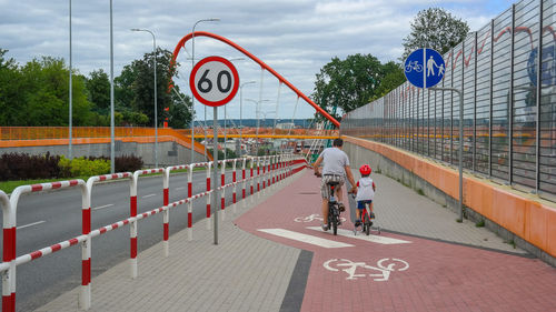 Rear view of father and son riding bicycle in city