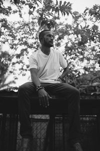 Young man looking away while sitting on seat