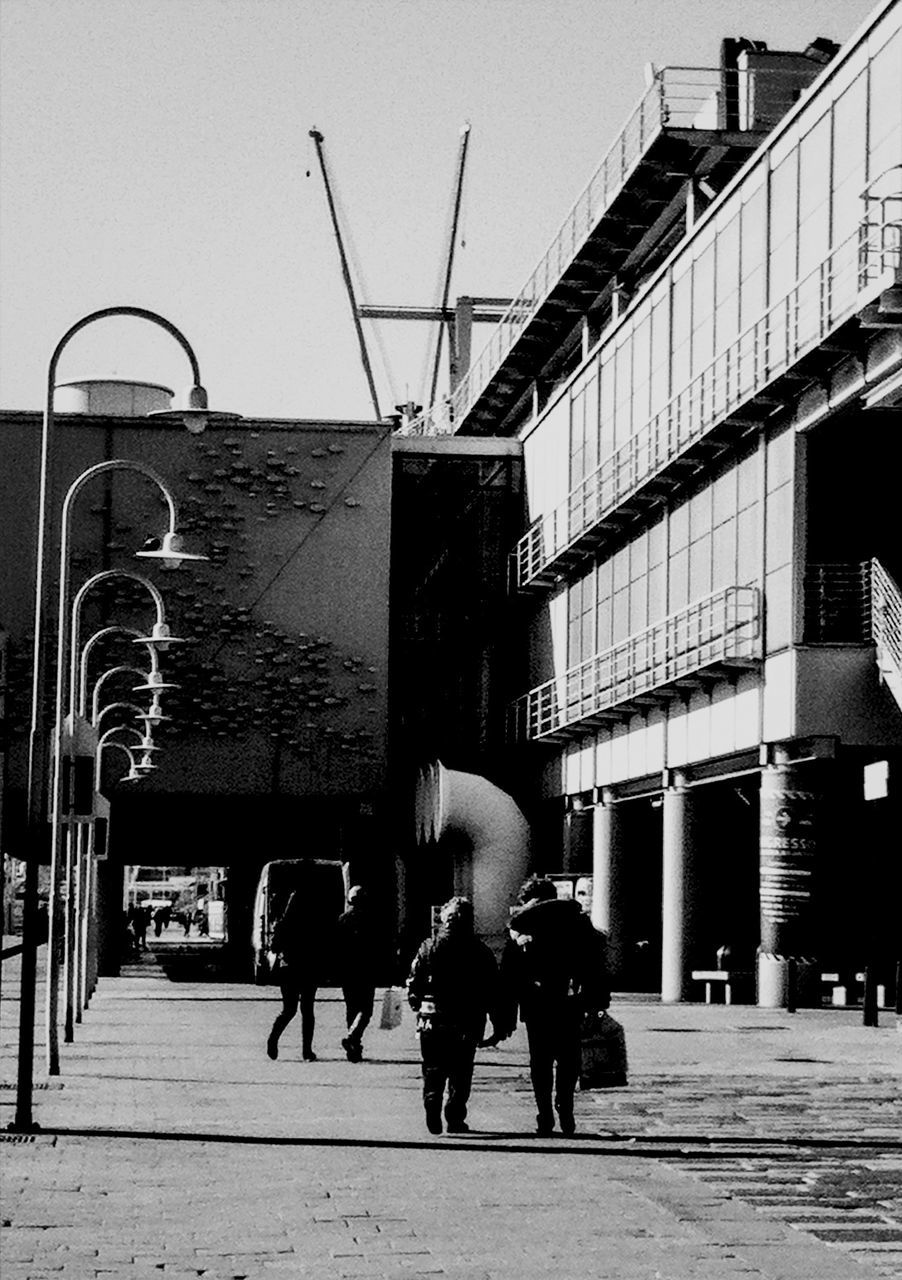 architecture, built structure, building exterior, men, walking, city, full length, lifestyles, street, person, the way forward, city life, building, street light, railing, bicycle, sky, sidewalk