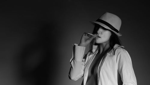 Sensuous woman smoking cigarette against wall