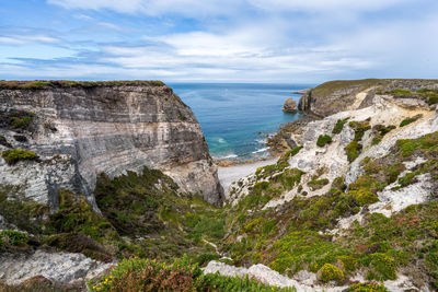 Scenic view of sea by cliff against sky