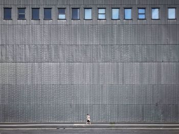 Side view of man walking against modern building