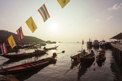 Boats moored at harbor against sky