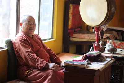 Portrait of monk sitting by window