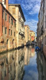 Canal amidst residential buildings against sky