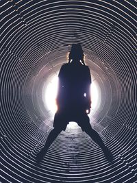 Rear view of silhouette man standing in tunnel