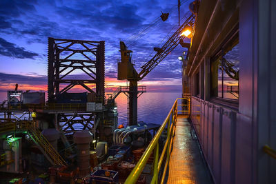 Illuminated pier amidst sea against sky at night