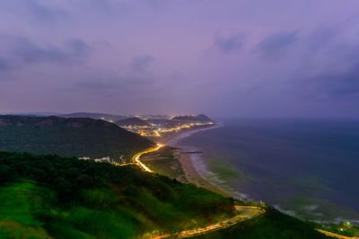 Aerial view of illuminated city against sky at sunset