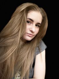 Portrait of young woman against black background