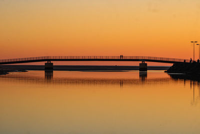 Bridge over sea against romantic sky at sunset