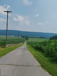 Road amidst field against sky