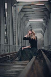 Woman sitting on railway bridge