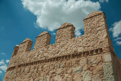 Battlement with merlons and crenels over rough stone wall encircling the town in avila, spain.