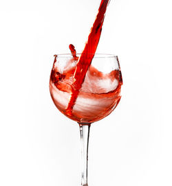 Close-up of wineglass on glass against white background