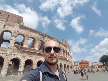 Portrait of man wearing sunglasses against coliseum