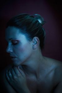 Close-up portrait of young woman against black background