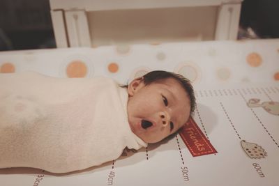 Portrait of cute baby lying on bed at home